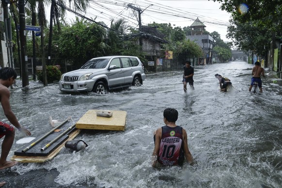 KEYPIX - epa12246808 A vehicle passes residents using floatation boards along a flooded road following heavy rains in Quezon City, Metro Manila, Philippines, 19 July 2025. Tropical Storm Wipha exited  ...