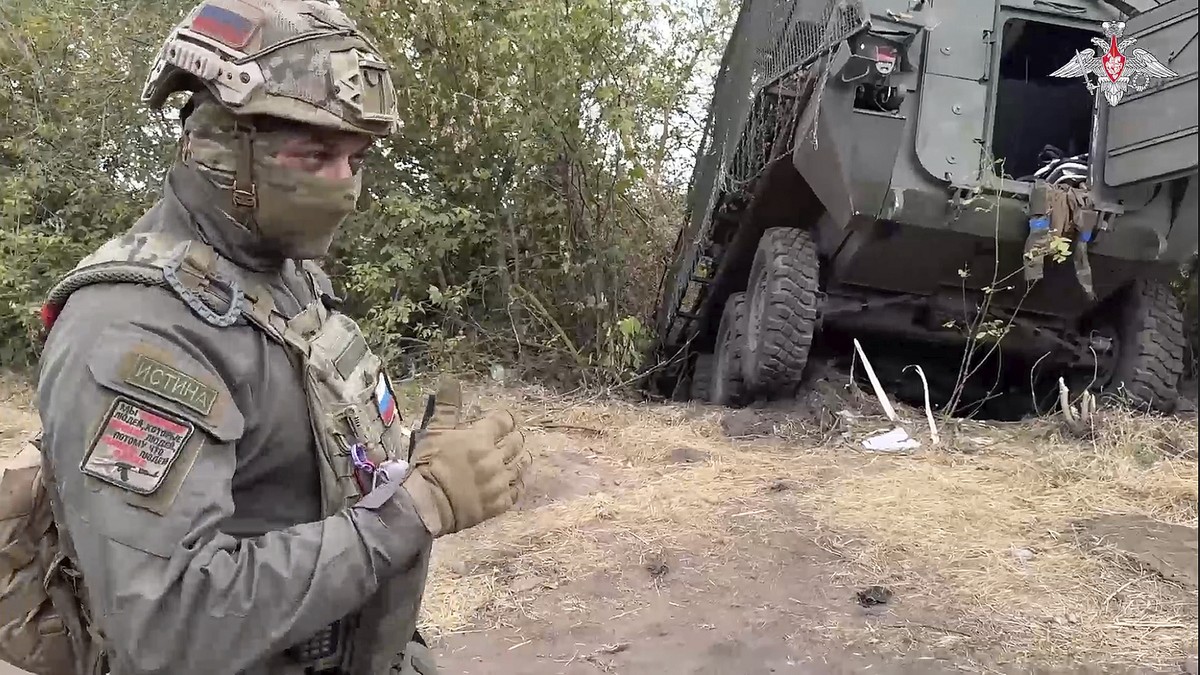 In this photo taken from video released by the Russian Defense Ministry on Friday, Sept. 13, 2024, a Russian soldier stands next to a damaged Ukrainian military vehicle in the Russian - Ukrainian bord ...