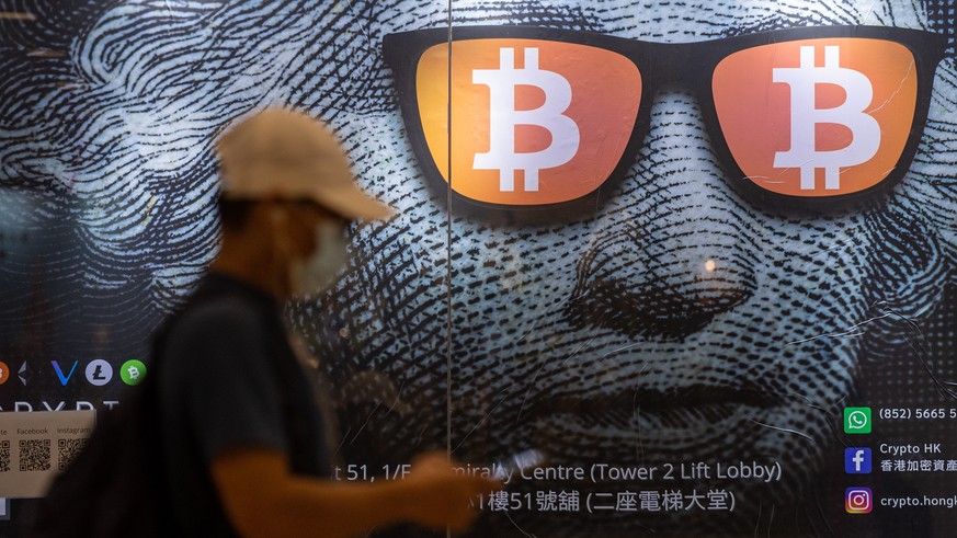 epaselect epa09486742 A man walks past an advertising poster for Bitcoins and cryptocurrencies in Hong Kong, China, 25 September 2021. On 24 September, China intensified the crackdown on cryptocurrenc ...