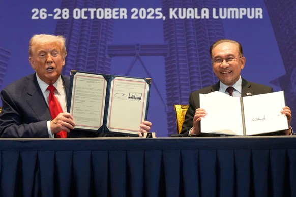 President Donald Trump and Malaysia&#039;s Prime Minister Anwar Ibrahim hold up documents after signing a trade agreement on the sidelines of the ASEAN Summit in Kuala Lumpur, Malaysia, Sunday, Oct. 2 ...