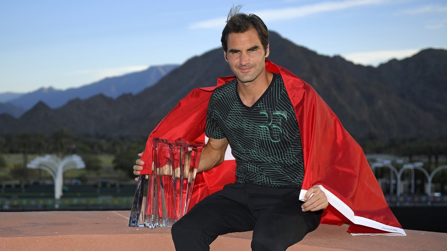 Roger Federer, of Switzerland, poses with his trophy and the Swiss flag at the BNP Paribas Open tennis tournament, Sunday, March 19, 2017, in Indian Wells, Calif. Federer defeated countryman Stan Wawr ...