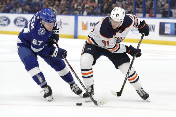 Tampa Bay Lightning's Mitchell Stephens, left, and Edmonton Oilers' Gaetan Haas, of Switzerland, reach for the puck during the first period of an NHL hockey game Thursday, Feb. 13, 2020, in Tampa, Fla ...