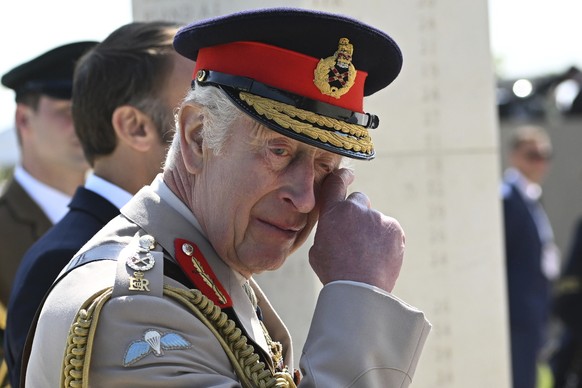 Britain&#039;s King Charles III gestures as he walks with France&#039;s President Emmanuel Macron by the memorial wall during the UK national commemorative event for the 80th anniversary of D-Day, hel ...