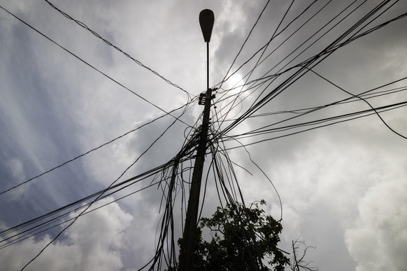 FILE - A utility pole with loose cables towers over a home in Loiza, Puerto Rico, Sept. 15, 2022. (AP Photo/Alejandro Granadillo, File)