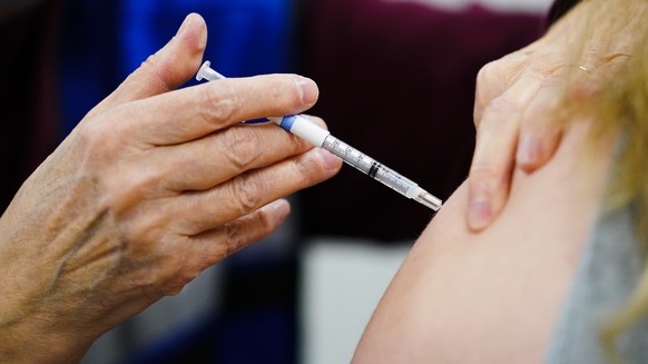 FILE - A health worker administers a dose of a COVID-19 vaccine during a vaccination clinic at the Keystone First Wellness Center in Chester, Pa., on Dec. 15, 2021. Government advisers are debating Tu ...