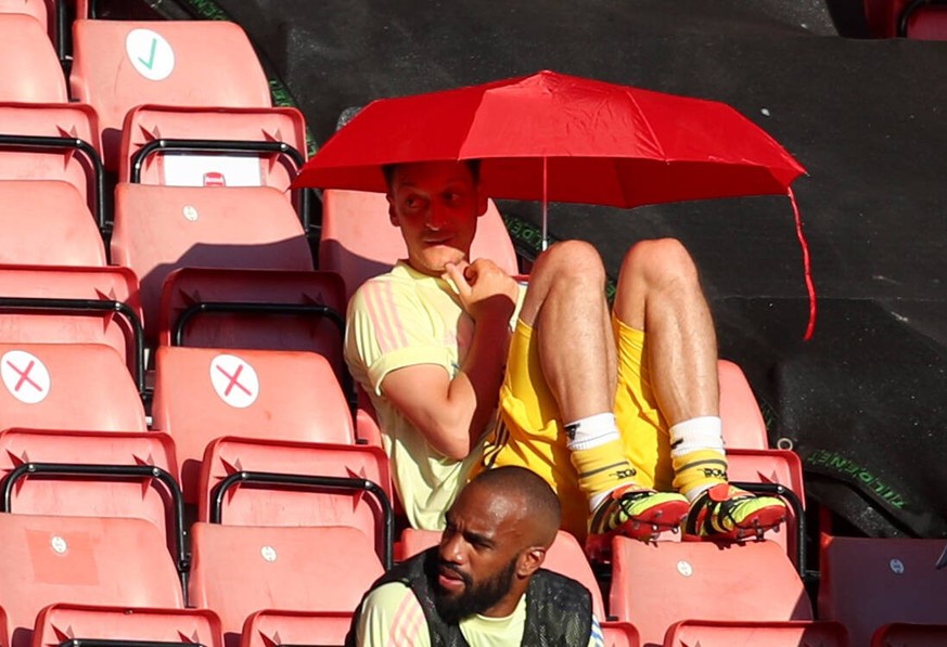 Southampton v Arsenal - Premier League - St Mary s Arsenal s Mesut Ozil shields from the sun under an umbrella in the stands during the Premier League match at St Mary s, Southampton. EDITORIAL USE ON ...