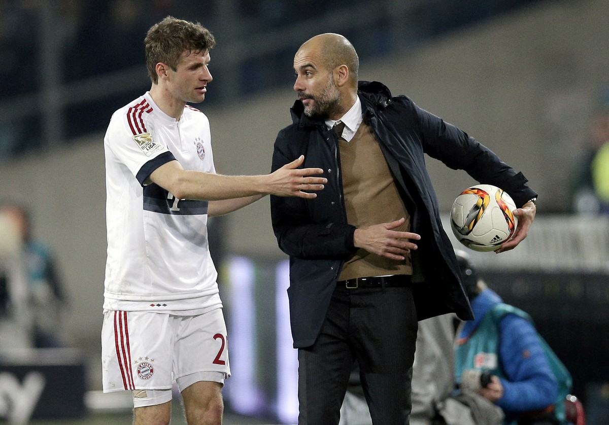 Bayern head coach pep Guardiola, right, takes away the ball from Bayern's Thomas Mueller, left, during the German Bundesliga soccer match between Hannover 96 and FC Bayern Munich in Hannover, Ger ...