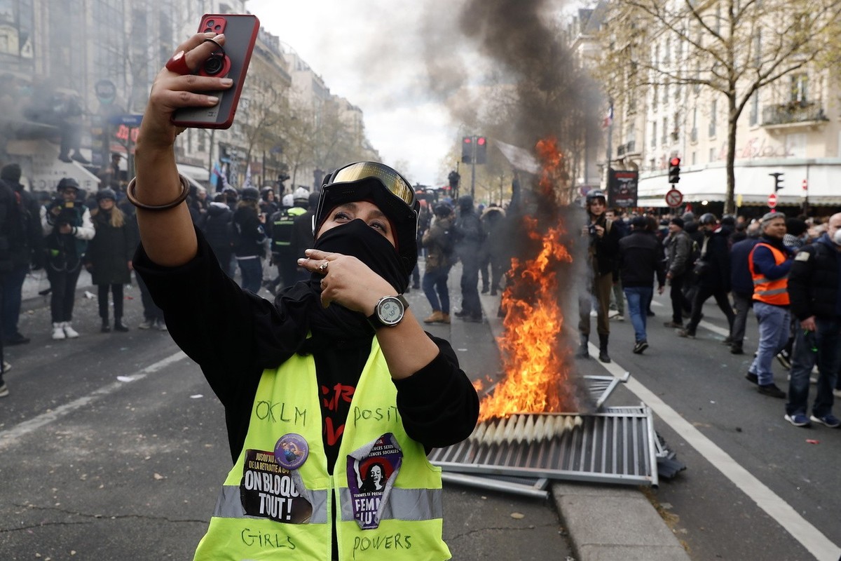 epa10561639 A protester takes a selfie as they clash with French riot Police during a rally against the government's reform to the pension system in Paris, France, 06 April 2023. Protests continu ...