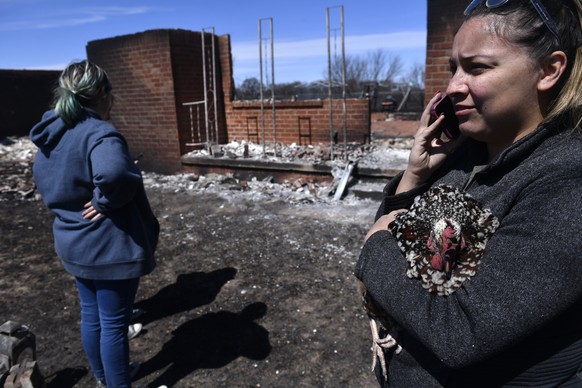 Priscilla Maynard holds a chicken while taking on the phone in front of a burned home Friday, March 18, 2022 near Carbon, Texas in Eastland County. Fire crews in West Texas hope to make progress Satur ...