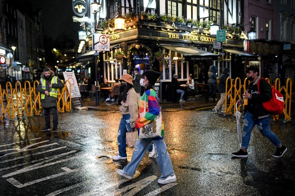 People wearing face masks to protect against coronavirus as they walk past a pub in Soho, London, Monday, Dec. 14, 2020. London and its surrounding areas will be placed under Britain&#039;s highest le ...