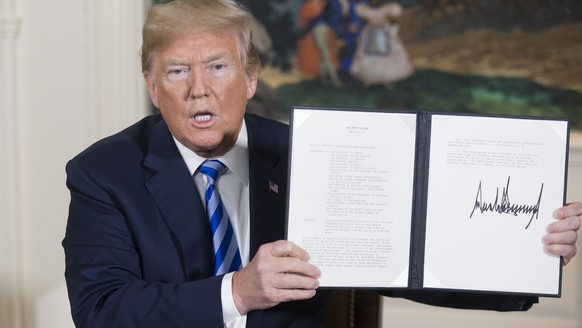 epa06720241 US President Donald J. Trump holds up a national security presidential memorandum on Iran that he just signed in the Diplomatic Reception Room of the White House in Washington, DC, USA, 08 ...