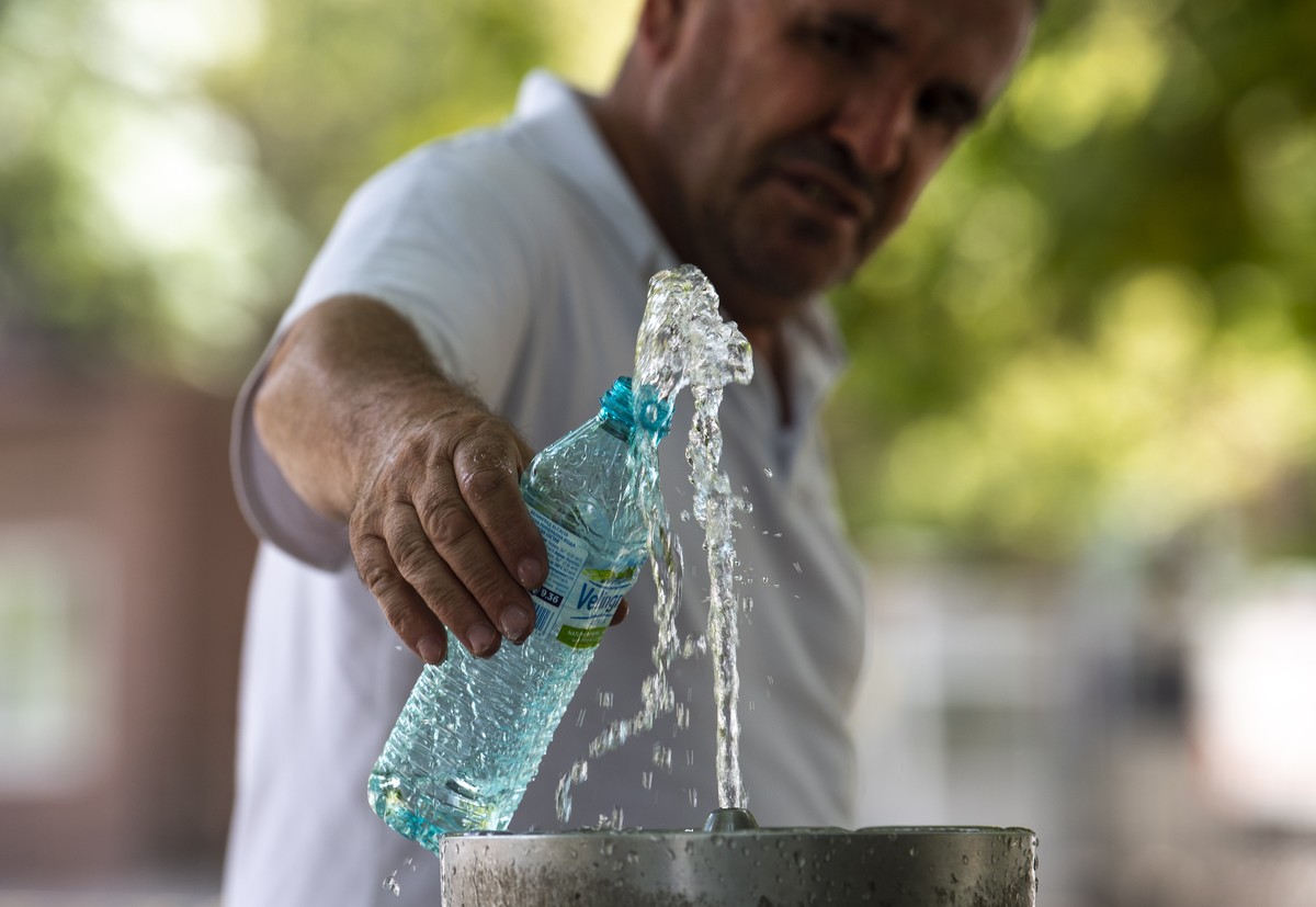 epa09388332 Man fills a bottle of water during a hot day with temperature over 40 degrees Celsius in Skopje, Republic of North Macedonia, 02 August 2021. July was very hot across the southern and sout ...