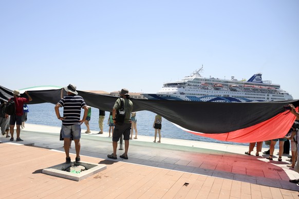 Protesters hold a Palestinian flag demonstrating as a cruise ship carrying Israeli tourists try to approach the Aegean Sea island of Syros, Greece, Tuesday, July 22, 2025. (Nikos Panagiotopoulos/InTim ...