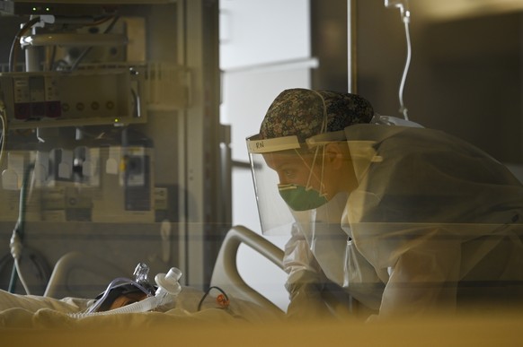 A critical care nurse with North Memorial Health Hospital leans down to speak to a COVID-19 patient under their care in Robbinsdale, Minn., Monday, Dec. 7, 2020. (Aaron Lavinsky/Star Tribune via AP)