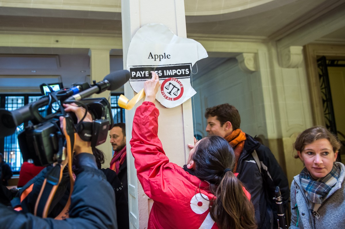 epa06363555 Activists of ATTAC, an anti-globalization organization hold banner reading 'Apple pay your taxes', in an Apple store to denounce the tax evasion used, according to them, by the A ...