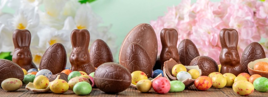 Easter background greeting card with holiday traditional confectionery, Easter egg hunt fun concept. Chocolate bunny, chocolate and candy Easter eggs on wooden background