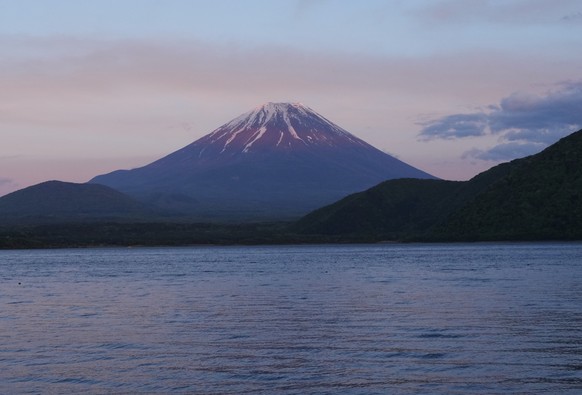 KEYPIX - Family members sit by Lake Motosu as the color of sunset is reflected on Mount Fuji, as seen from a campsite in Minobucho, west of Tokyo, Saturday, May 9, 2026. (KEYSTONE/AP Photo/Hiro Komae)