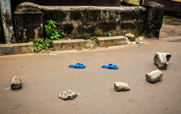 Bewohner von Freetown habe die Schuhe eines Mannes unter Ebola-Verdacht mit Steinen markiert.