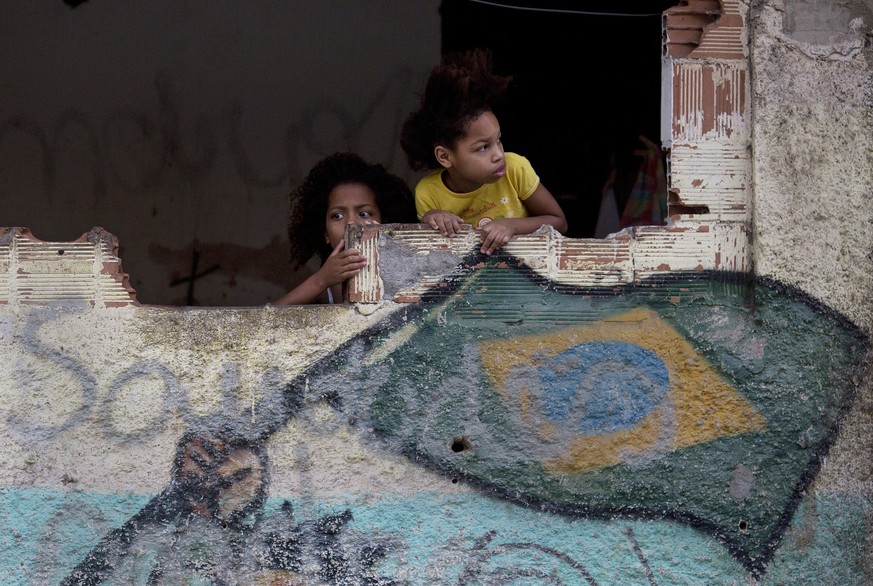 In this Aug. 20, 2017 photo, girls watch a demonstration calling for peace, demanding an end to the violence between drug gangs and police, at the Manguinhos slum, in Rio de Janeiro, Brazil. Amid a na ...