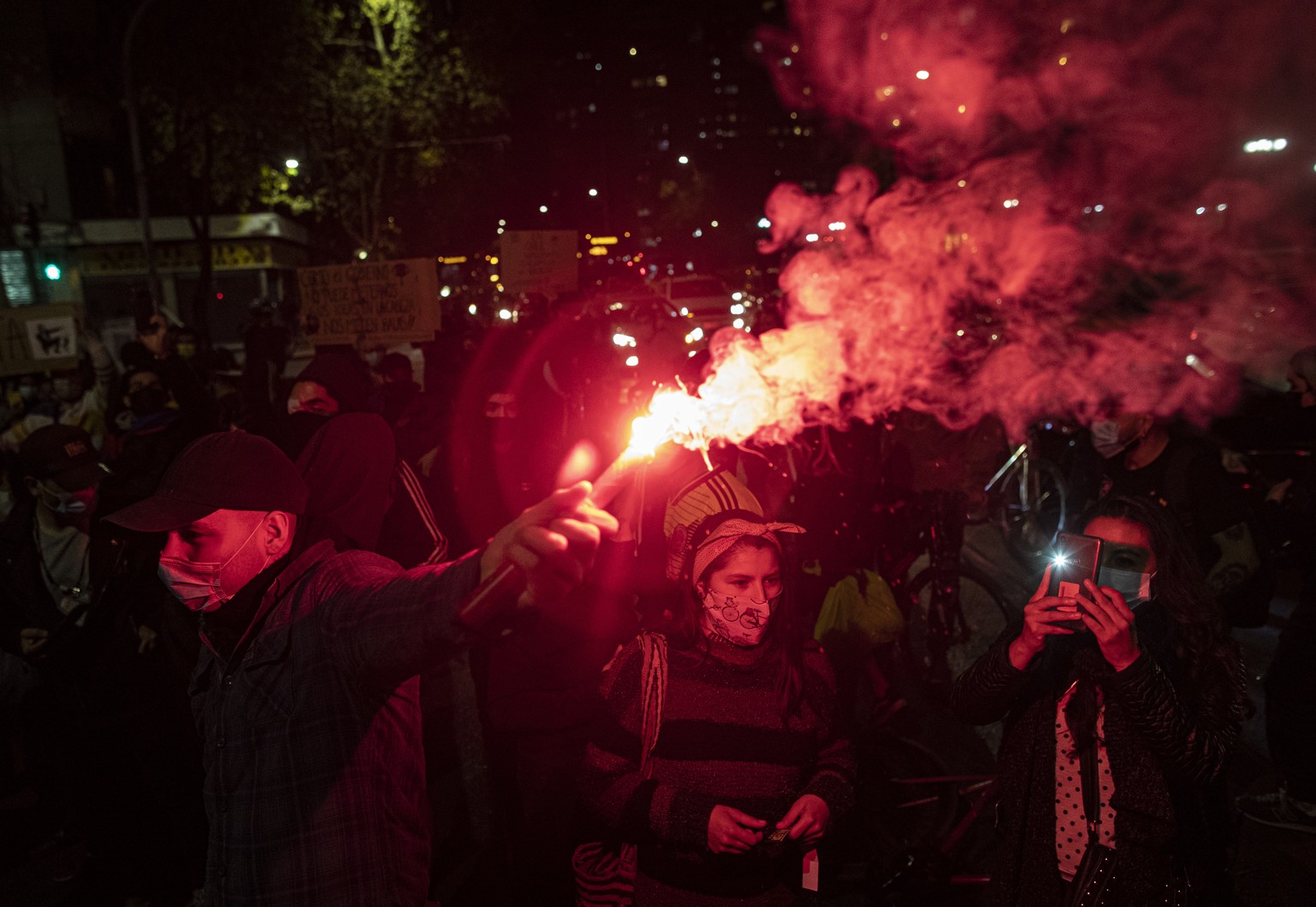 A man lights a flare during a vigil by Colombian residents in Chile against the violence happening in Colombia, in Santiago, Chile, May 05, 2021. The protests began after Colombia���s government propo ...