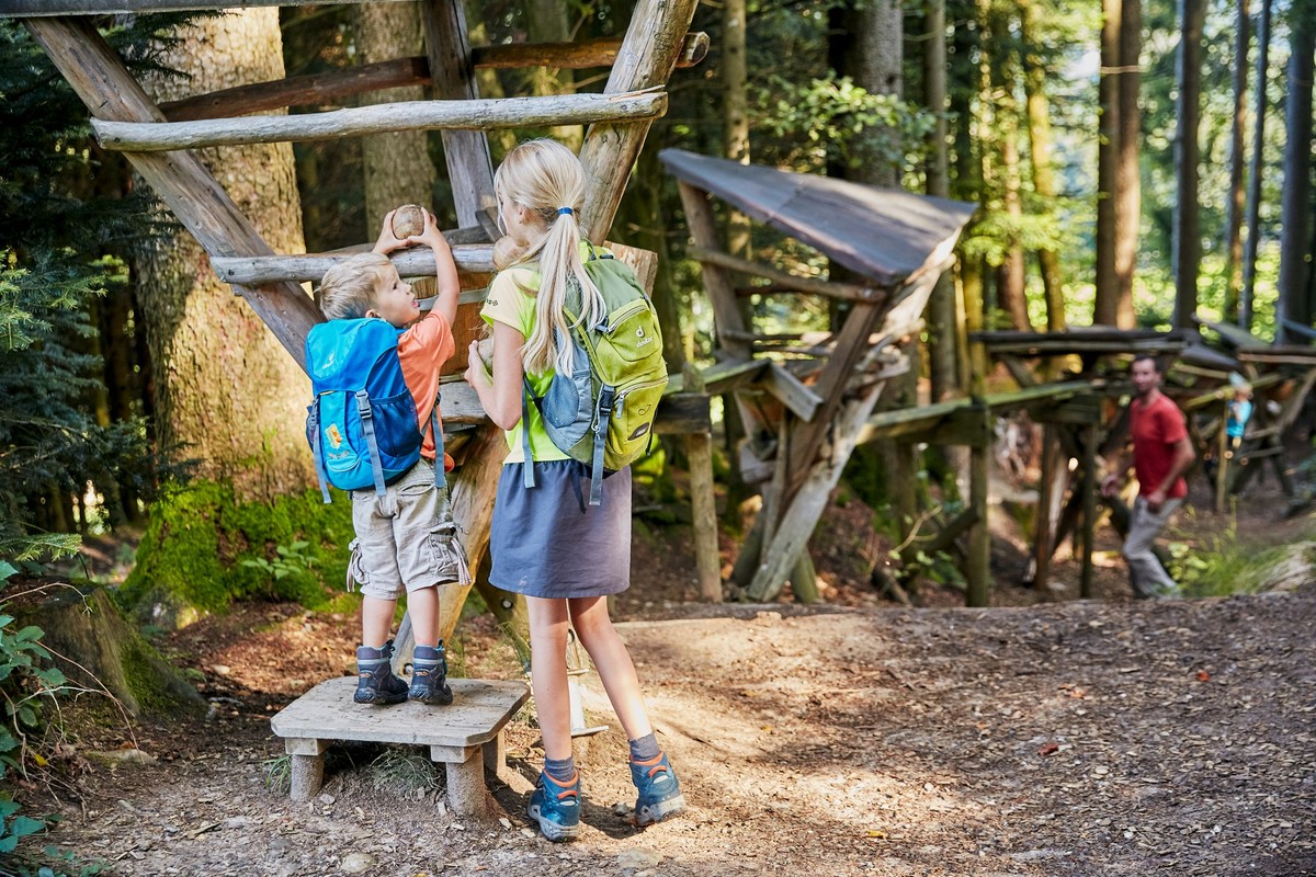 Familie im Zyberliland Romoos. Immer wieder machen die Bärgmandli mit kleinen roten Füsschen auf sich aufmerksam und führen die neugierigen Kinder durch die malerische Natur zu den sechs verschiedenen ...