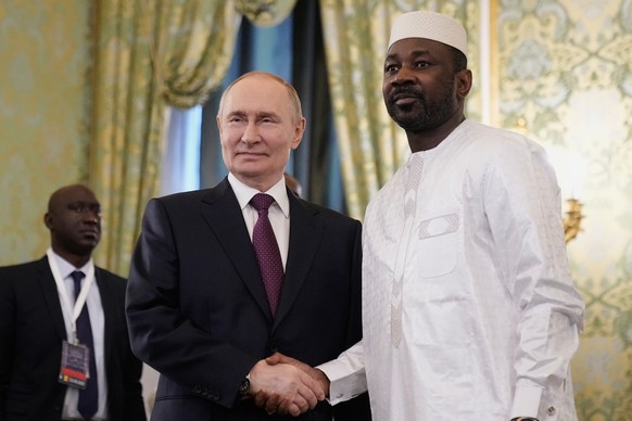 epa12192792 Russian President Vladimir Putin (C) shakes hands with Interim President of the Republic of Mali Assimi Goita (R) during their meeting at the Kremlin in Moscow, Russia, 23 June 2025. EPA/P ...