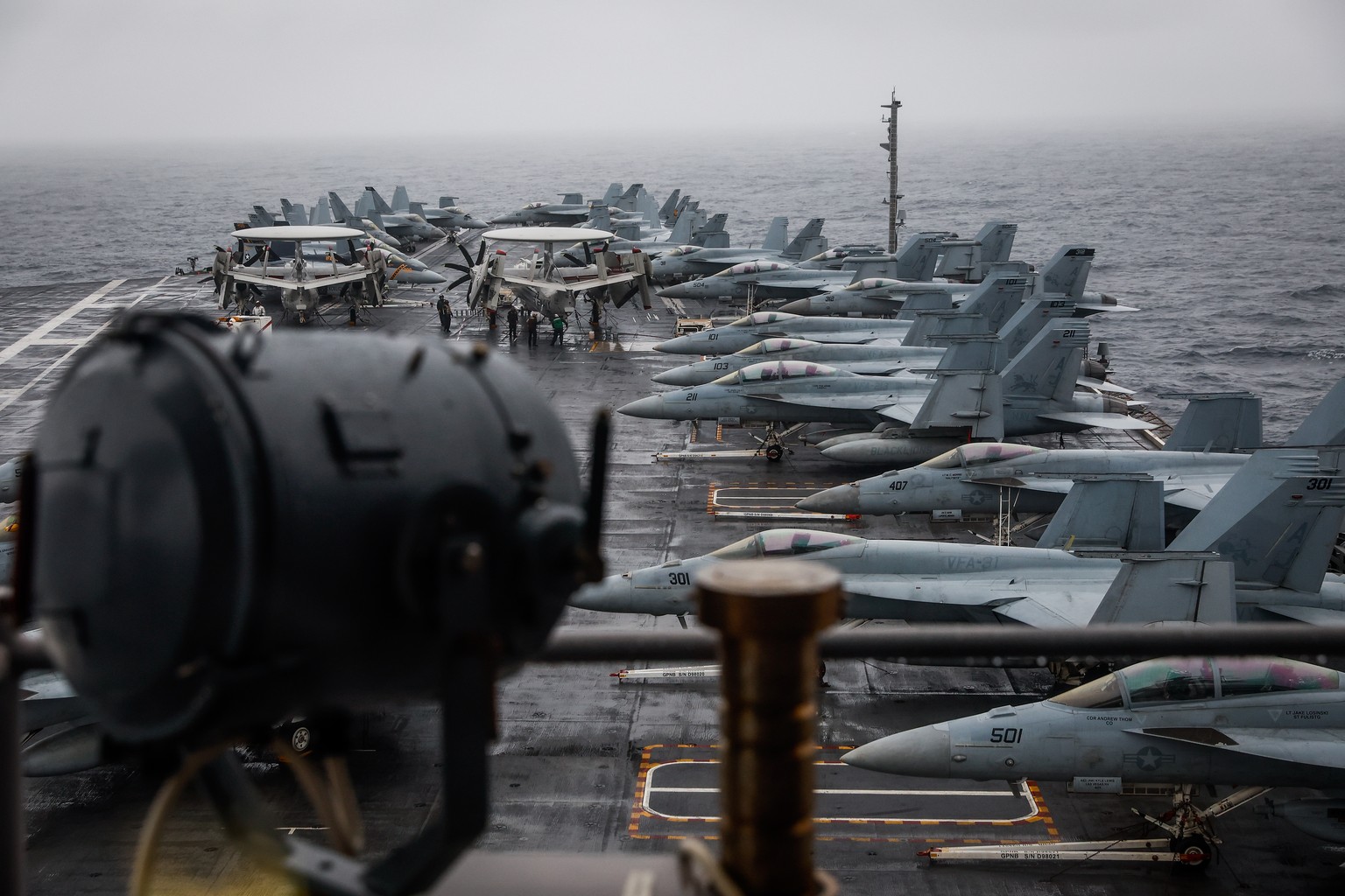 epa10303843 F-18 fighter jets stand on deck while US Navy service members maintain them during Sunday break on the side of an exercise called Silent Wolverine on the USS Gerald R. Ford aircraft Carrie ...