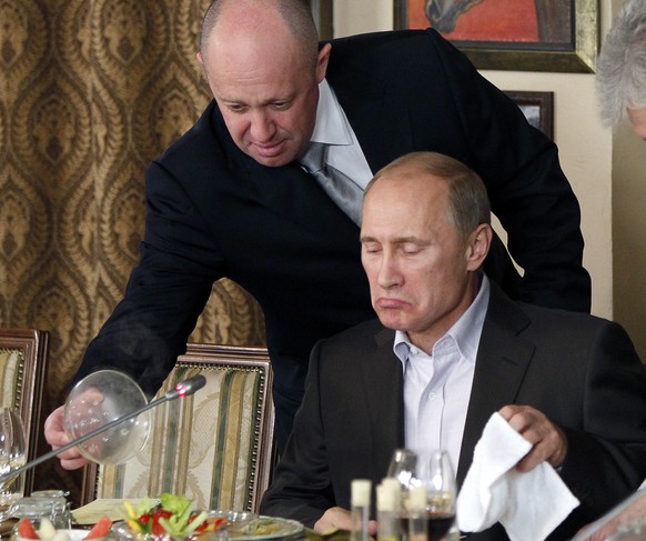 FILE - In this Friday, Nov. 11, 2011, file photo, Yevgeny Prigozhin, left, serves food to Russian Prime Minister Vladimir Putin during dinner at Prigozhin&#039;s restaurant outside Moscow, Russia. Pro ...