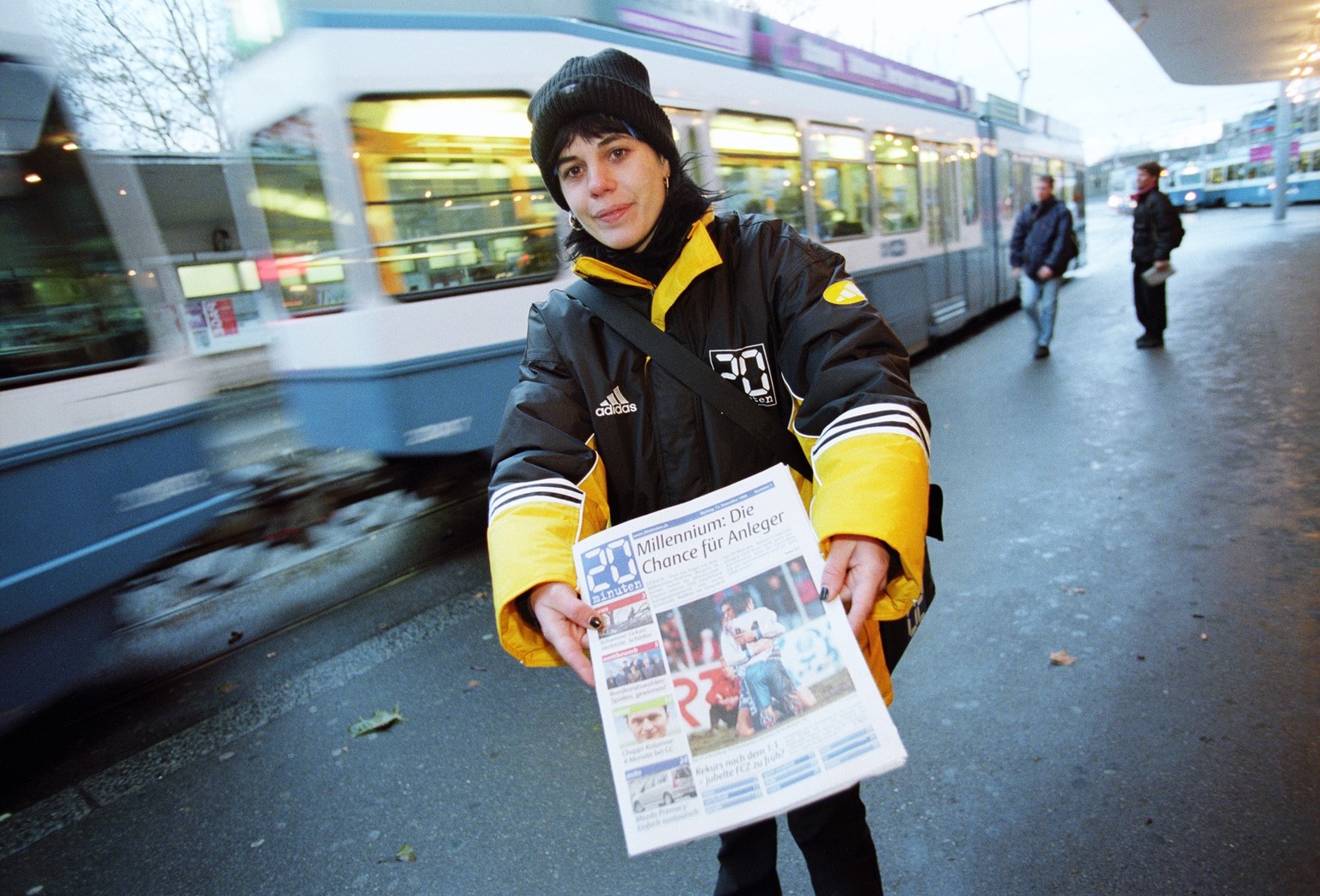 Eine Verteilerin der Gratiszeitung "20 Minuten" bietet am Tag der Lancierung des Gratisblatts beim Bellevue in Zuerich die Zeitung Passanten an, aufgenommen am 13. Dezember 1999. (KEYSTONE/C ...