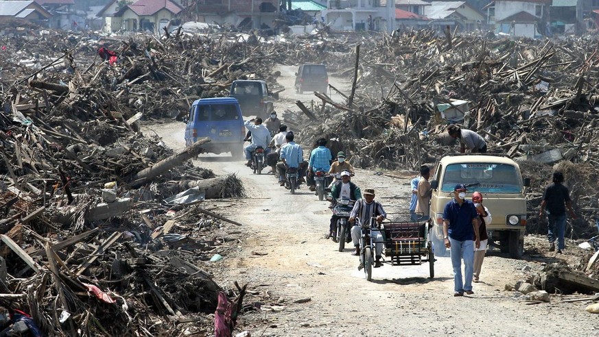 Acehnese commuters pass between files of woods and metal beams along Uleelheule district, in Banda Aceh on Sunday, 23 January 2005. The Indonesian death toll from last month&#039;s earthquake and tsun ...