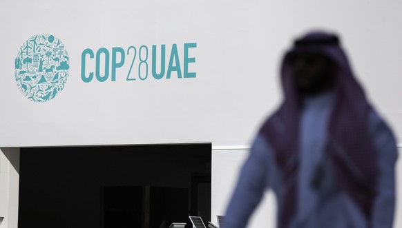 epa11001585 A man walks in front of the COP28 logo at Expo City Dubai, the venue of the 2023 United Nations Climate Change Conference (COP28), in Dubai, UAE, 29 November 2023. The 2023 United Nations  ...