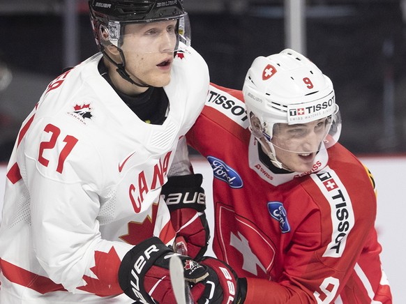 Switzerland goaltender Kevin Pasche looks for the puck as Canada&#039;s Nathan Gaucher, center, and Switzerland&#039;s Brian Zanetti battle in front of him during the second period of an IIHF World Ju ...