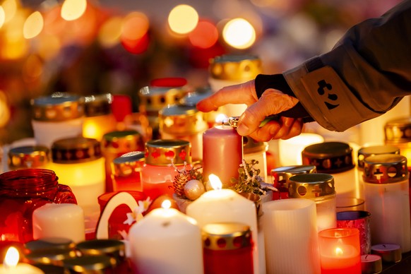 epa12626279 A person lights candles in tribute to the victims after the fire at the 'Le Constellation' bar and lounge, in Crans-Montana, Switzerland, 04 January 2026. At least 40 people lost ...