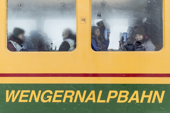 Ski fans sit in the &quot;Wengernalpbahn&quot; train down to Wengen after the cancellation of the men&#039;s downhill race of the FIS Alpine Ski World Cup at the Lauberhorn, in Wengen, Switzerland, Sa ...