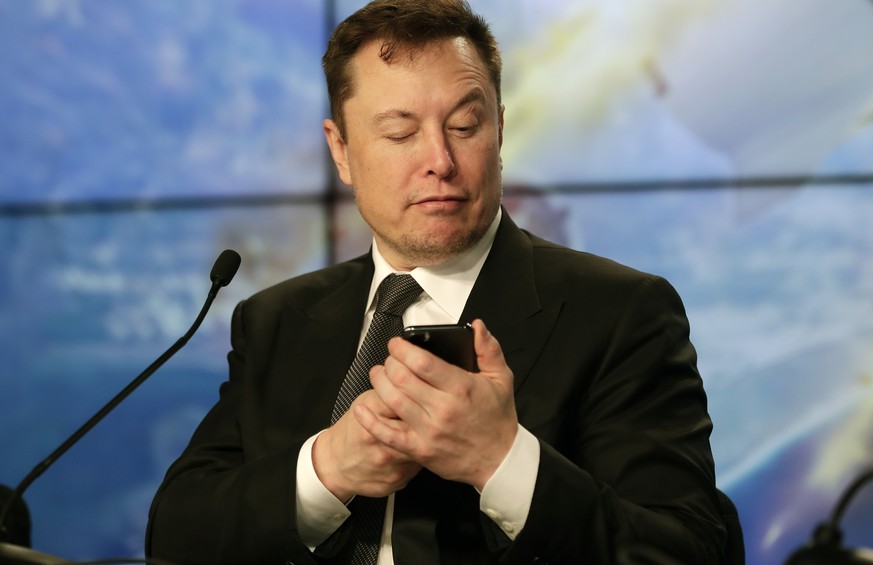 FILE - Elon Musk founder, CEO, and chief engineer/designer of SpaceX jokes with reporters as he pretends to search for an answer to a question on a cell phone during a news conference after a Falcon 9 ...