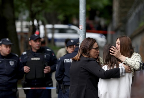 epa10605740 Teachers comfort students near Vladislav Ribnikar primary school in Belgrade, Serbia, May 03, 2023. A teenage suspect opened fire, causing one death and several injuries, according to ...