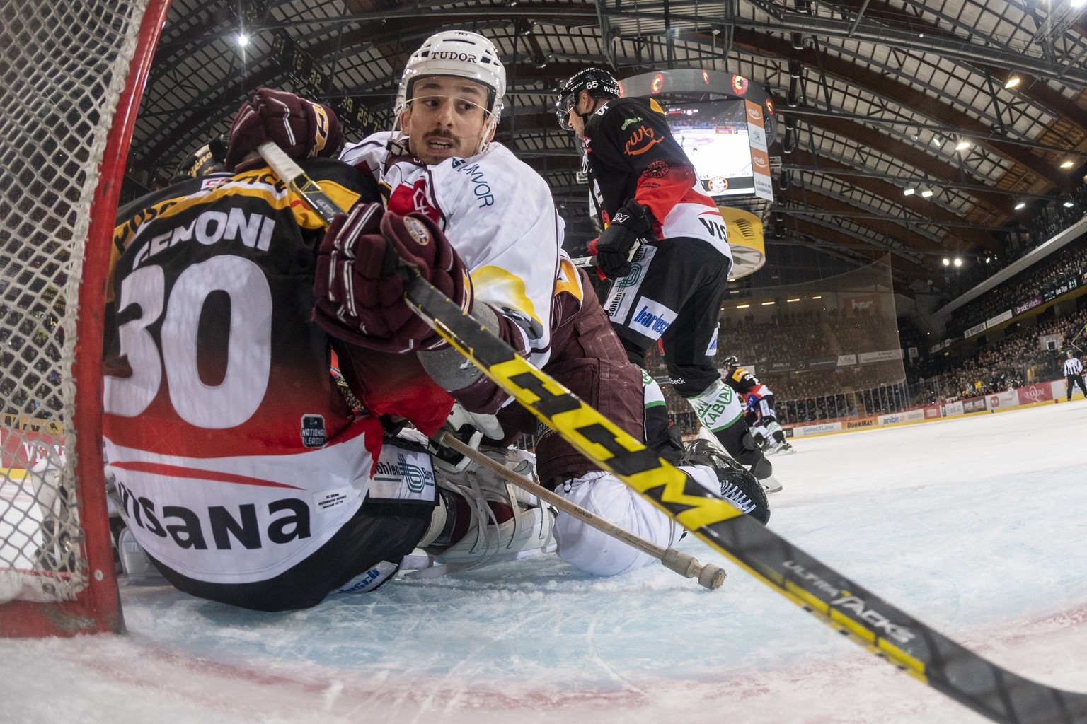 Servettes Noah Rod, Mitte, bedraengt Bern Goalie Leonardo Genoni, links, im dritten Eishockey Playoff-Viertelfinalspiel der National League zwischen dem SC Bern und dem Geneve-Servette HC am Donnersta ...