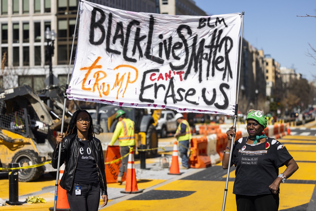 epa11954207 Protestors hold a sign as local government crews begin reconstruction of the Black Lives Matter (BLM) Plaza across from the White House in Washington, DC, USA, 10 March 2025. Republican la ...