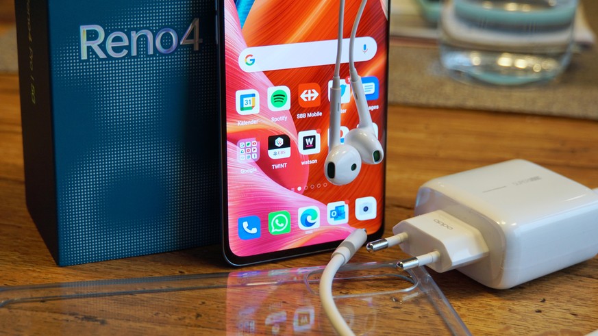 Oppo Reno 4 Pro mit Schnellladegerät und Kopfhörern.