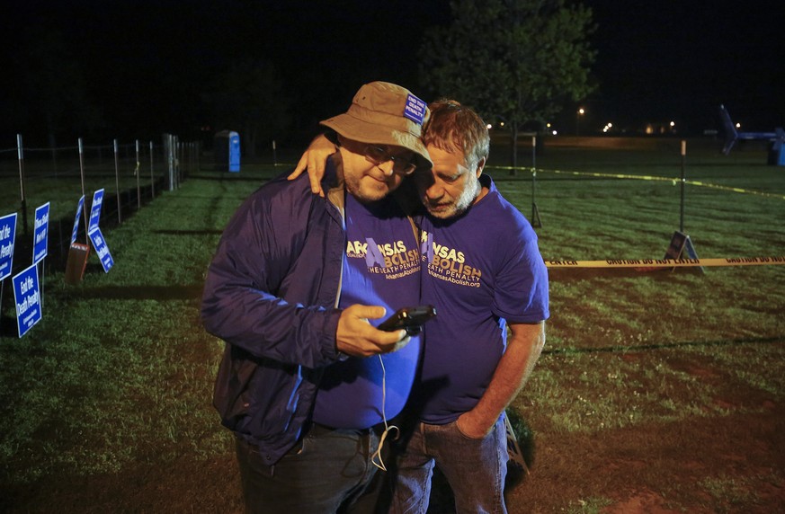 Anti-death penalty supporter Randy Gardner, right, embraces Abraham Bonowitz, left, after they read on his phone the 11:45 p.m., decision to halt the execution in their taped off &quot;protest corral& ...