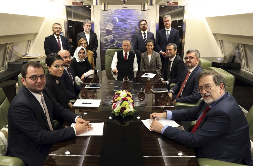 Turkey&#039;s President Recep Tayyip Erdogan, center, is surrounded by journalists and pro-government academicians in his plane en route back from Baku, Azerbaijan, Tuesday, Oct. 15, 2019. The White H ...