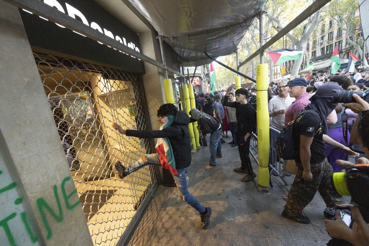 epa12431173 A man tries to break the door of a McDonals during a demonstration following a rally organized in support of Palestine in Barcelona, Spain, 04 October 2025. EPA/MARTA PEREZ