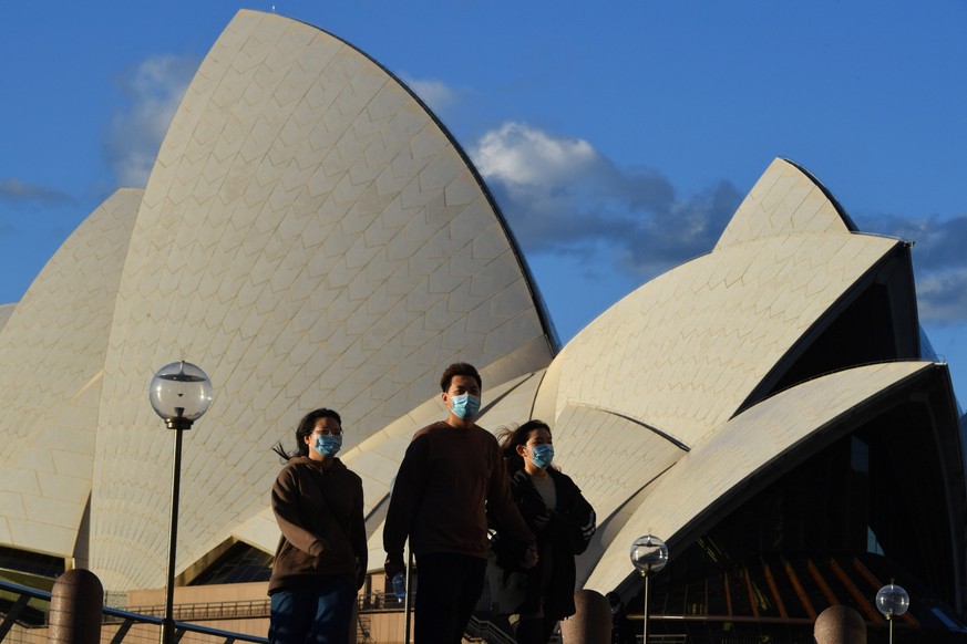 epa09302260 Pedestrians wearing face masks walk past the Sydney Opera House in Sydney, New South Wales (NSW), Australia, 26 June 2021. All of greater Sydney, the Central Coast, the Blue Mountains and  ...