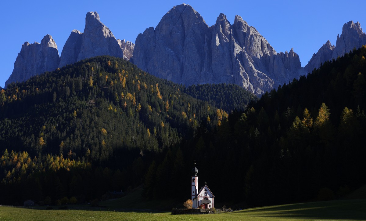 The sun sets at the St. Johann chapel and the Dolomites mountains in St. Maddalena, St. Magdalena, Val di Funes (Villnoess), in northern Italian province of South Tyrol, Italy, Thursday, Oct. 28, 2021 ...