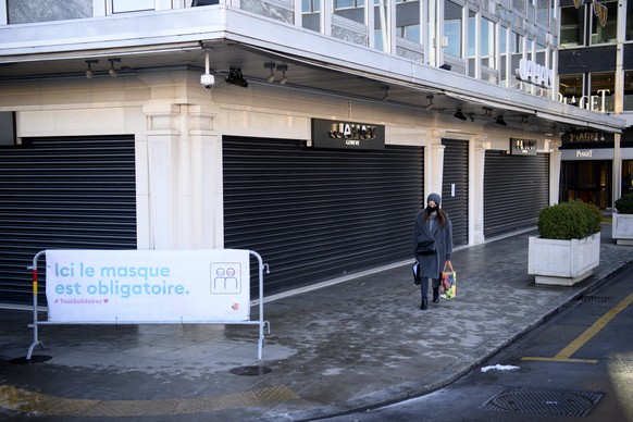 epa08945850 Aedestrian wearing protective face mask walks in front of a closed Jahan jewellery shop the first day of the closure of non-essential shops during the coronavirus disease (COVID-19) outbre ...