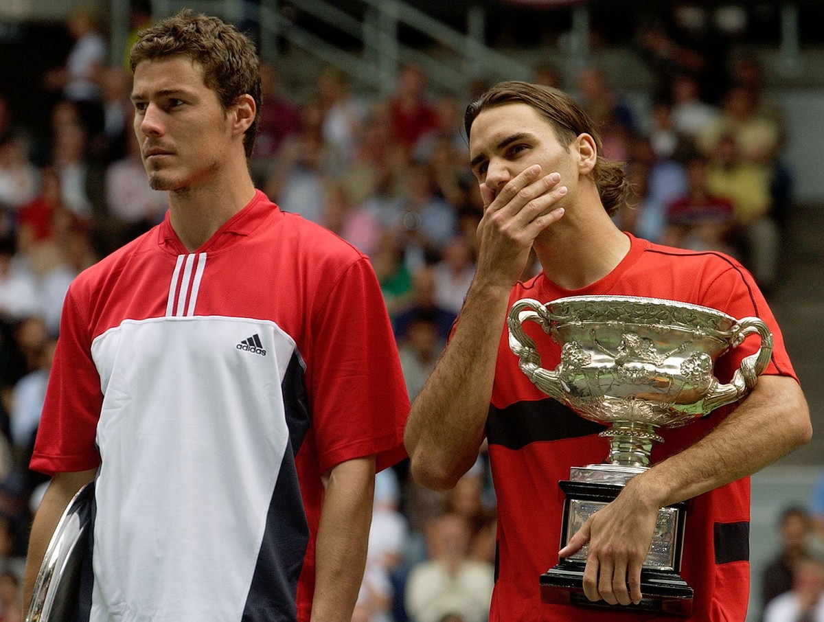 Roger Federer of Switzerland, right, holds the trophy after winning the men's final against Marat Safin, left, of Russia at the Australian Open in Melbourne, Australia, Sunday, Feb. 1, 2004. Fede ...