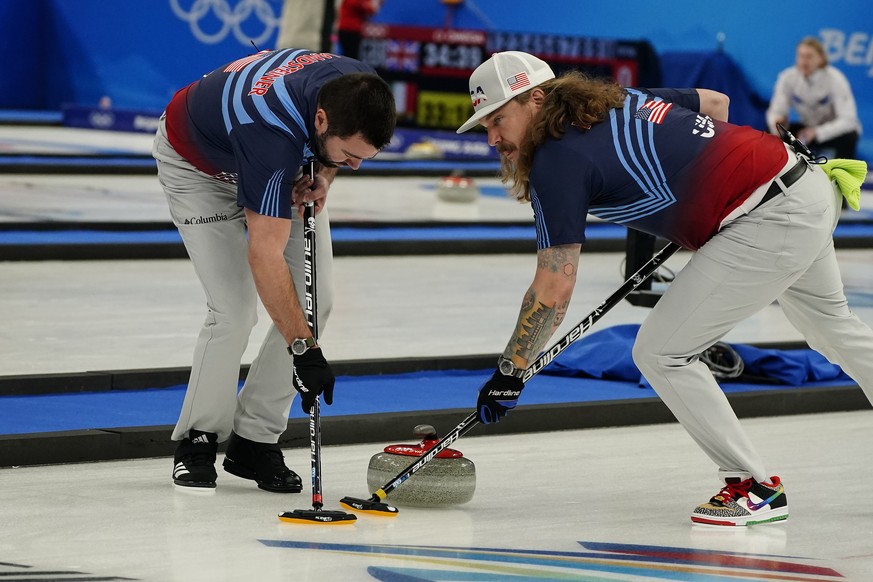 The United States&#039; John Landsteiner, left, and Matt Hamilton, right, sweep a rock during a men&#039;s curling match against Sweden at the Beijing Winter Olympics Thursday, Feb. 10, 2022, in Beiji ...