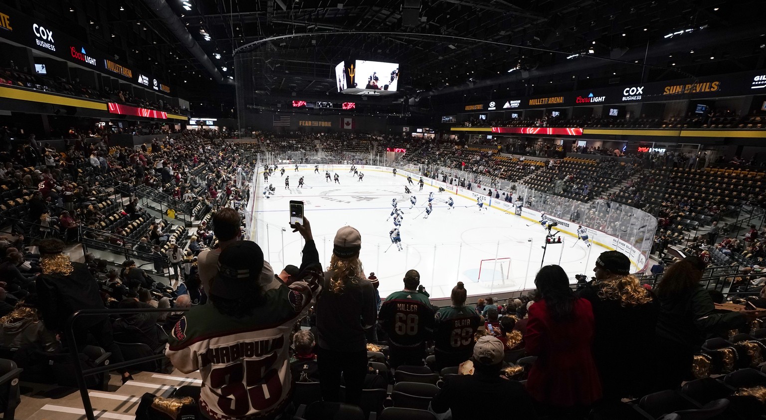 FILE - Fans watch as players warm up prior to the Arizona Coyotes&#039; home-opening NHL hockey game against the Winnipeg Jets at the 5,000-seat Mullett Arena in Tempe, Ariz., Oct. 28, 2022. The Coyot ...