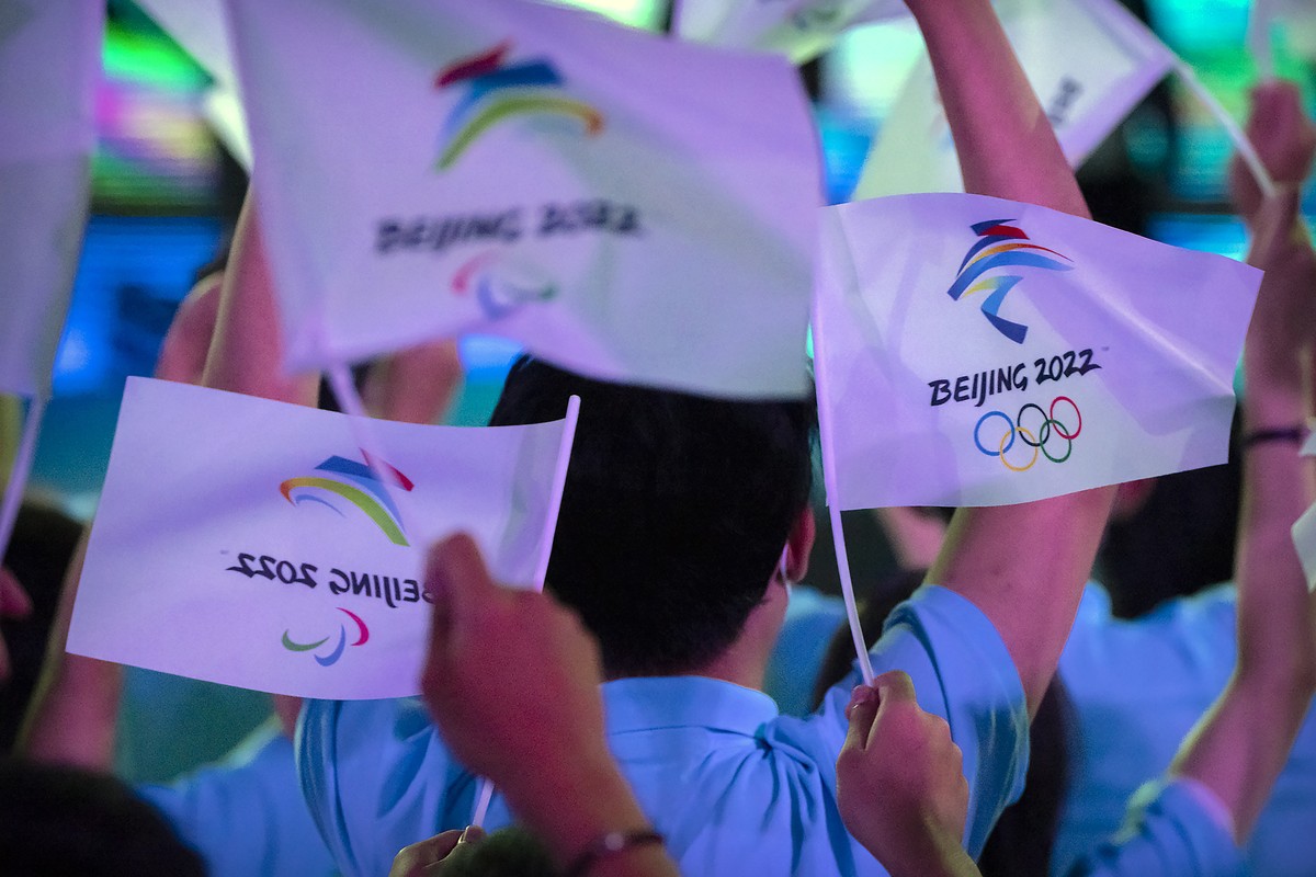 FILE - Participants wave flags with the logos of 2022 Beijing Winter Olympics and Paralympics before a launch ceremony to reveal the motto for the Winter Olympics and Paralympics in Beijing on Sept. 1 ...