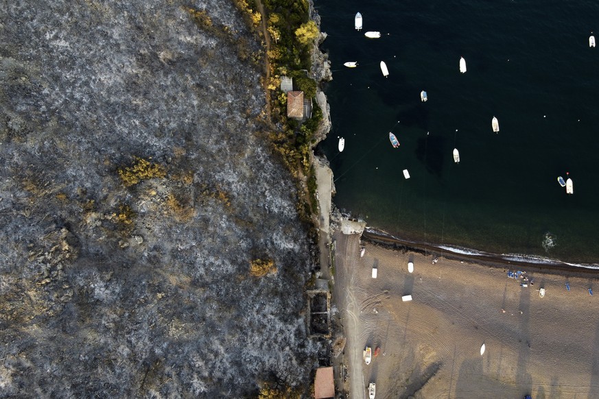 A burnt mountain over a beach in Agia Anna village on Evia island, about 148 kilometers (92 miles) north of Athens, Greece, Tuesday, Aug. 10, 2021. As Greece&#039;s massive wildfires appeared to large ...
